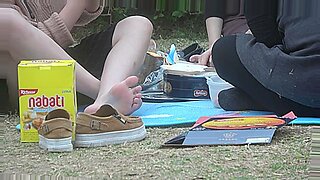 Seorang gadis Asia muda memamerkan kakinya di taman.